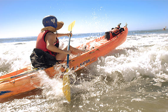 person on kayak crashing through wave
